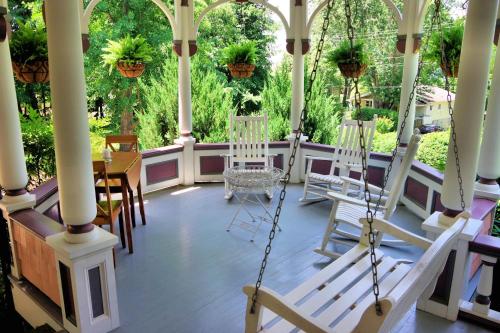 a porch with white chairs and a swing at Beaufort House Inn in Asheville