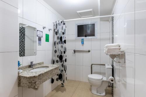 La salle de bains est pourvue de toilettes, d'un lavabo et d'une télévision. dans l'établissement Hotel Baviera Iguassu, à Foz do Iguaçu