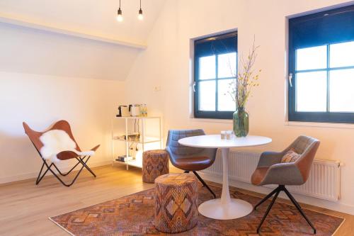 ein Wohnzimmer mit einem Tisch, Stühlen und Fenstern in der Unterkunft De Gouden Wilg in Lunteren