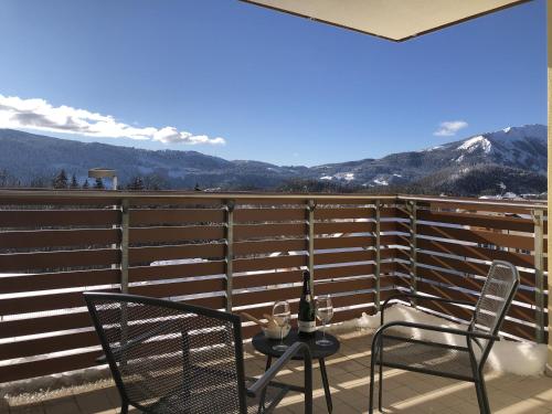 a balcony with two chairs and a table with a bottle of wine at Residence Aurora in Lavarone