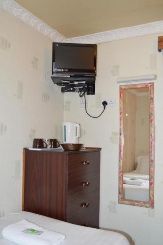 a bedroom with a television and a dresser with a mirror at Fortuna House Hotel in Blackpool