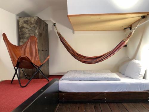 ein Schlafzimmer mit einer Hängematte, einem Bett und einem Stuhl in der Unterkunft Schiffshotel "Schlafen im Hafen" in Hamburg
