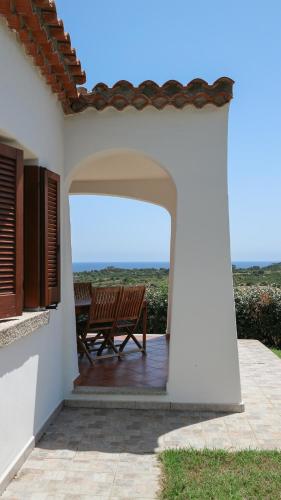a patio with a bench and a view of the ocean at Marea in Tanaunella