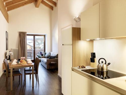 cocina y sala de estar con mesa y hervidor de agua. en Residence Aurora, en Lavarone