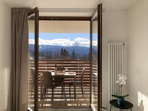 a glass door leading to a balcony with a table and chairs at Residence Aurora in Lavarone