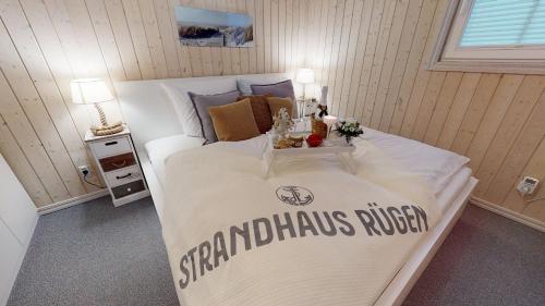 a bed with a white comforter with a sign on it at Strandhaus Rügen - Meerblick, Sauna, Kamin & Whirlpool in Baabe