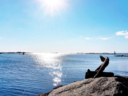 um pau sentado numa rocha perto da água em 4 person holiday home in H n em Hönö