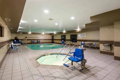 a swimming pool with a blue chair in a hotel room at Holiday Inn Express Bloomington West by IHG in Bloomington