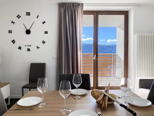 a dining room with a clock and a table with wine glasses at Residence Aurora in Lavarone
