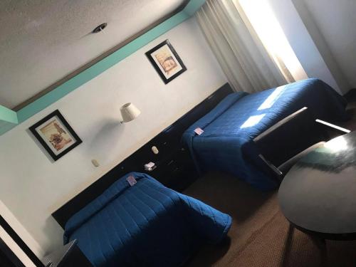 a bedroom with a blue bed and a couch at Hotel Real Rex in León