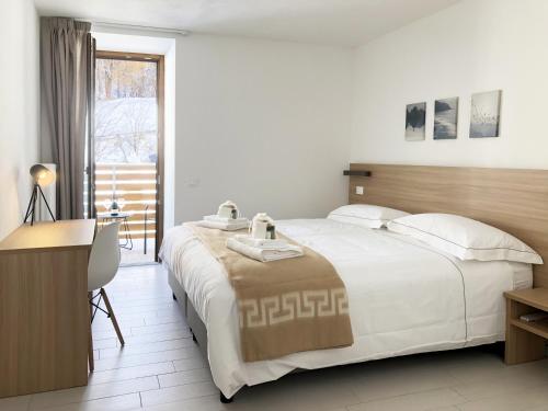 a bedroom with a bed and a desk and a window at Residence Aurora in Lavarone