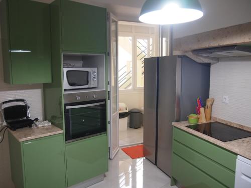 a kitchen with green cabinets and a microwave at Green View Home in Lisbon