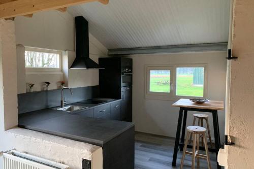 a kitchen with a sink and a counter with a table at Karibu de Stallen (met Sauna en Stoom douche) in Daarle