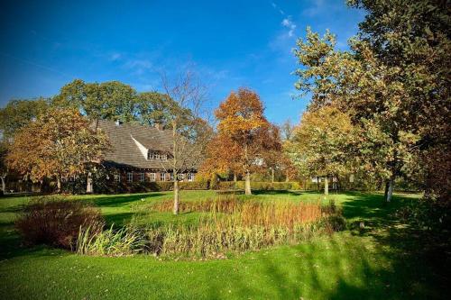 a house in the middle of a yard with trees at Karibu de Stallen (met Sauna en Stoom douche) in Daarle