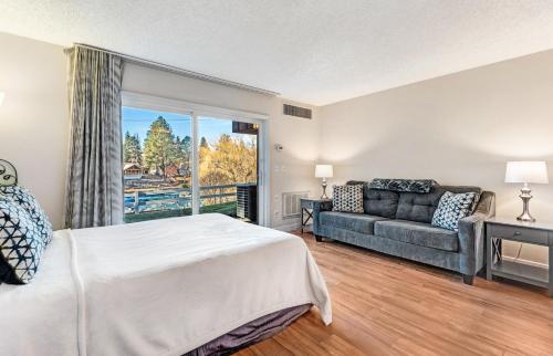a bedroom with a bed and a couch and a window at Bend Riverside Condos Near Downtown Bend in Bend