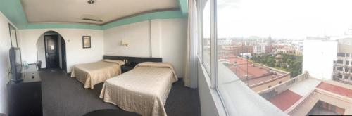 a hotel room with two beds and a large window at Hotel Real Rex in León