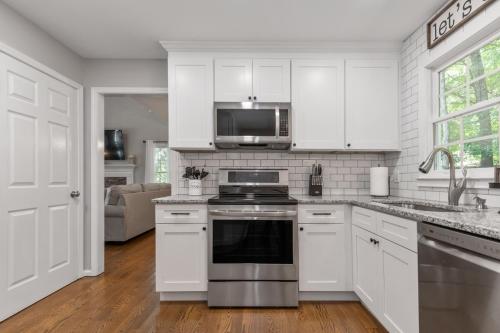 a kitchen with white cabinets and a stove top oven at Explore Historic DT In This Cozy Open Air 5BR Stay in Cartersville