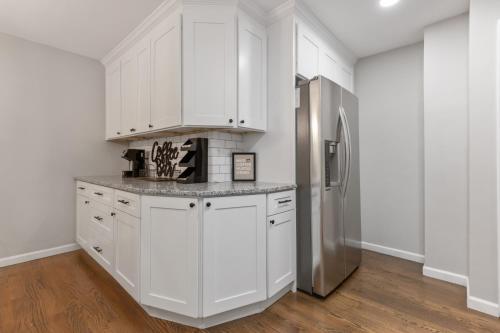 a kitchen with white cabinets and a stainless steel refrigerator at Explore Historic DT In This Cozy Open Air 5BR Stay in Cartersville
