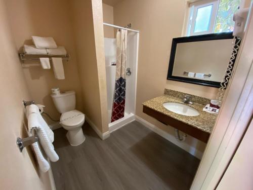W łazience znajduje się toaleta, umywalka i prysznic. w obiekcie Pacific Inn w mieście Grover Beach