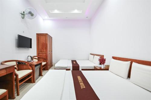 a hotel room with two beds and a desk at Paradise Hotel in Củ Chi