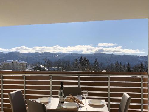 a table with chairs and a bottle of wine on a balcony at Residence Aurora in Lavarone