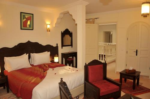 a bedroom with a large bed and a red chair at Hotel Riad Ben Atar in Essaouira