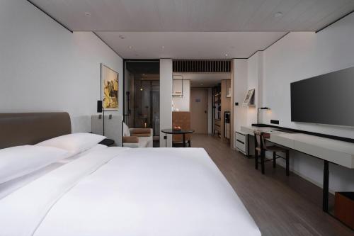 a bedroom with a large bed and a flat screen tv at THE MUMIAN HOTEL Shenzhen luohu in Shenzhen