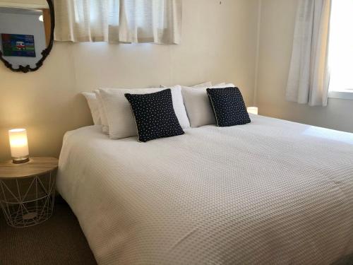 une chambre avec un grand lit blanc avec des oreillers dans l'établissement High Country Cottage, à Twizel