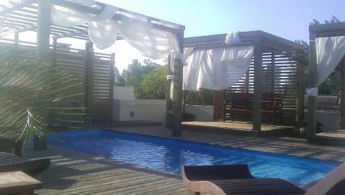 a swimming pool with a wooden deck and a pavilion at De Rose Praia Hotel in Torres