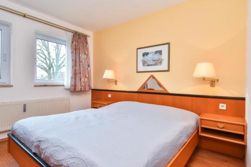 een slaapkamer met een groot bed en 2 ramen bij Ferienwohnung Ostsee-Hecht mit Balkon im Kaiserhof 2 in Kellenhusen
