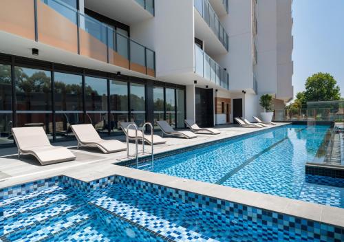 a swimming pool with chairs next to a building at Caroline Serviced Apartments Sandringham in Sandringham