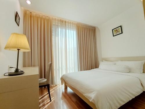 um quarto com uma cama, um candeeiro e uma janela em Citihouse Ho Chi Minh Apartment em Cidade de Ho Chi Minh