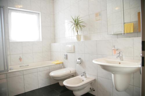 a white bathroom with a sink and a toilet at Hotel Wilhelmshöhe in Neuenrade