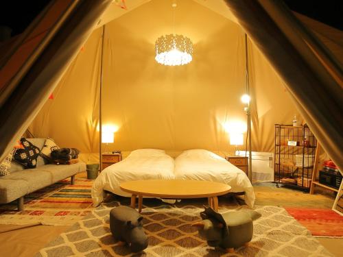 a bedroom with a bed and a table in a tent at Fukiagehama Field Hotel in Ichikikushikino