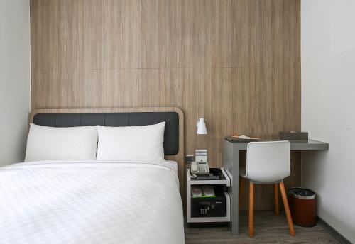 a bedroom with a bed and a desk and a chair at CityInn Hotel Plus - Taichung Station Branch in Taichung