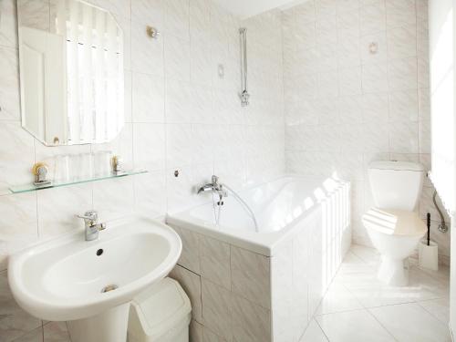 a white bathroom with a sink and a tub and a toilet at Hotel Milan Vopicka in Hluboká nad Vltavou