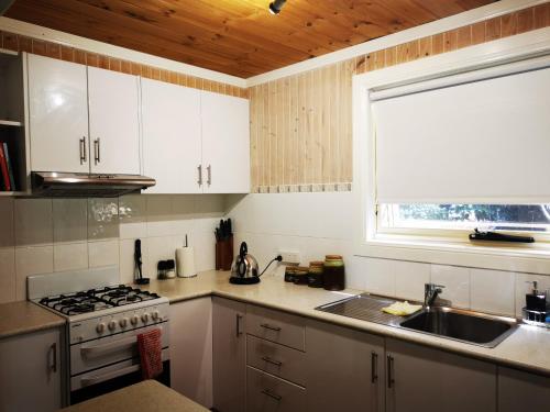 a kitchen with a stove and a sink and a window at Peaceful cabin in a rural setting 2km from CBD in Tamworth