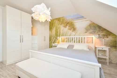 ein weißes Schlafzimmer mit einem Bett und einem Kronleuchter in der Unterkunft Waldstraße 16 Wolkenlos in Kellenhusen
