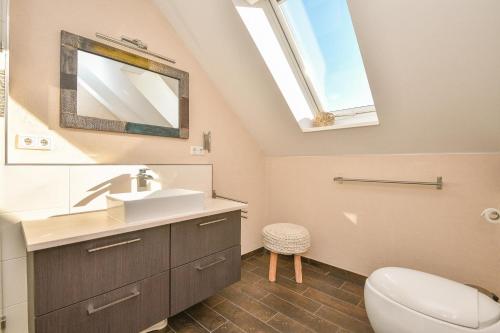 ein Bad mit einem Waschbecken, einem WC und einem Fenster in der Unterkunft Waldstraße 16 Wolkenlos in Kellenhusen