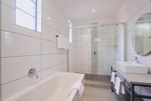 a white bathroom with a tub and a sink at THE Pretoria Hotel in Pretoria