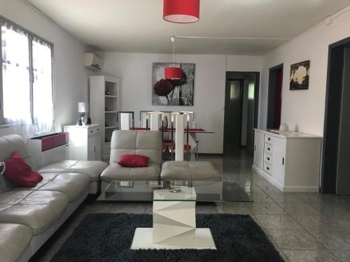 a living room with a white couch and a glass table at Les Bungalows du Mont-Auban in Sainte-Clotilde