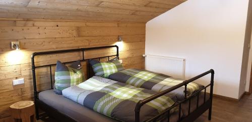 a bed in a room with a wooden wall at Chalet Weitsee in Reit im Winkl