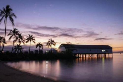 a building on the shore of a body of water with palm trees at Tropical One Bedroom Apartment at The Mediterranean in Port Douglas