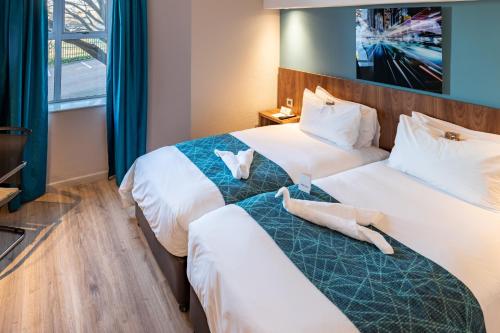 two beds in a hotel room with towels on them at Town Lodge Johannesburg Airport in Kempton Park