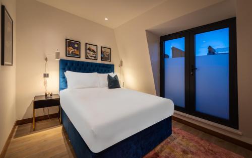 a bedroom with a large bed and a large window at Hux Hotel, Kensington in London