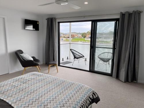 a bedroom with a bed and a balcony with a view at Reflections on the water in Port Macquarie