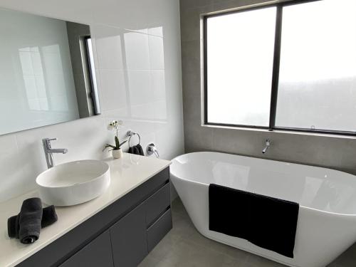 a bathroom with a large white tub and a sink at Reflections on the water in Port Macquarie