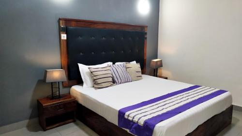 a bedroom with a large bed with a black headboard at IMOLEASE Kouessi Menontin in Cotonou