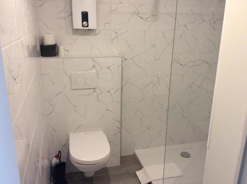 a white bathroom with a toilet and a shower at Appartement Val Rose II, 7de verdieping in Blankenberge