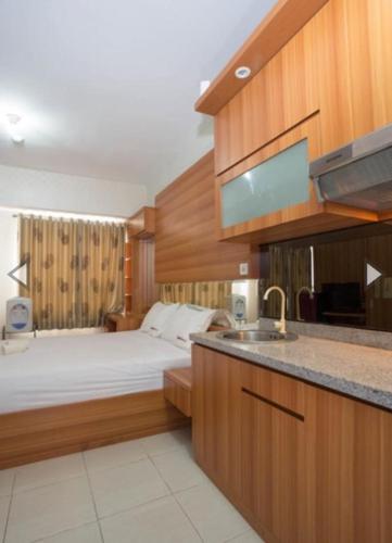 a bedroom with a bed and a kitchen with a sink at Apartemen Taman Melati Margonda by Winroom in Kukusan